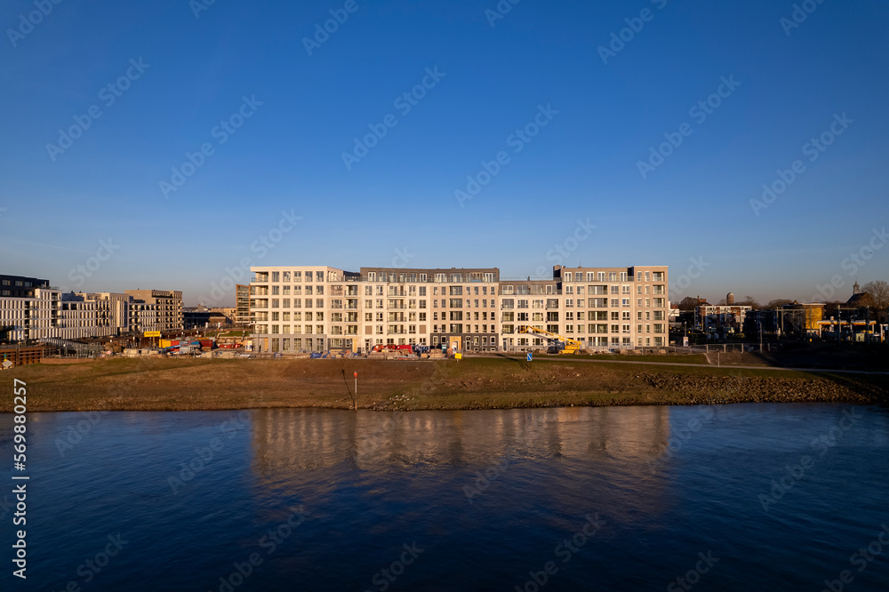 Luxury residential Kade Zuid apartment complex construction at riverbank of river IJssel reflecting in the water contrasted against a clear blue sky