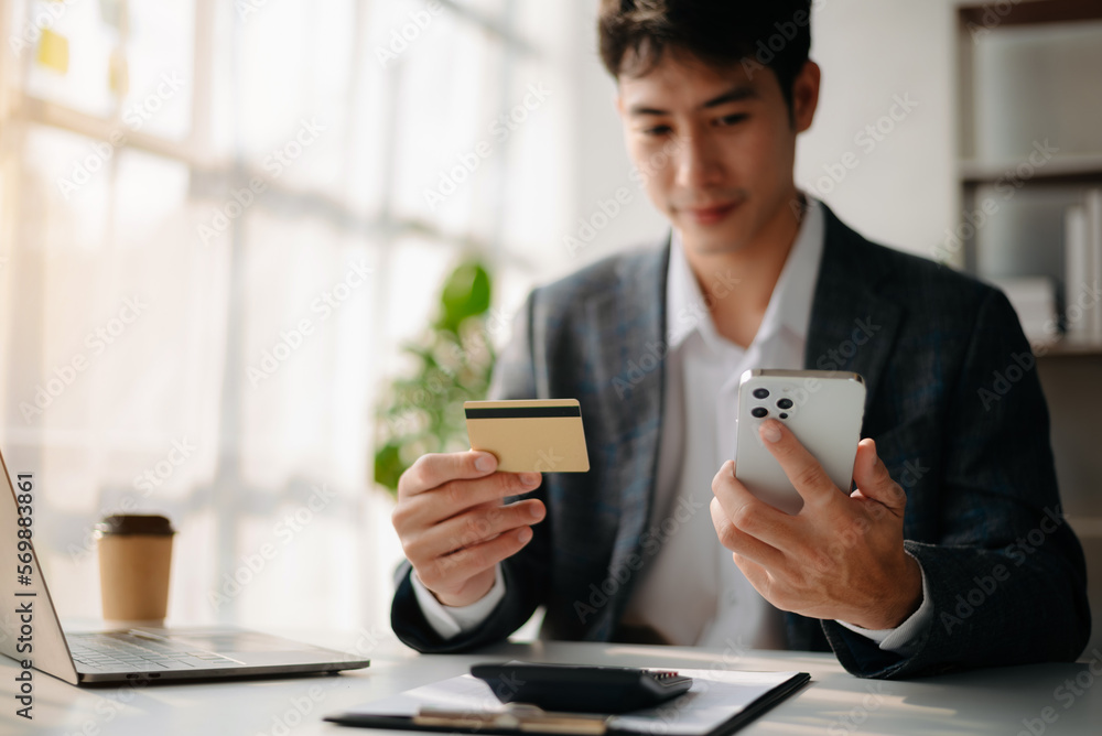 Man using smart phone for mobile payments online shopping,omni channel,sitting on table Man using smart phone for mobile payments online shopping,omni channel,sitting on table