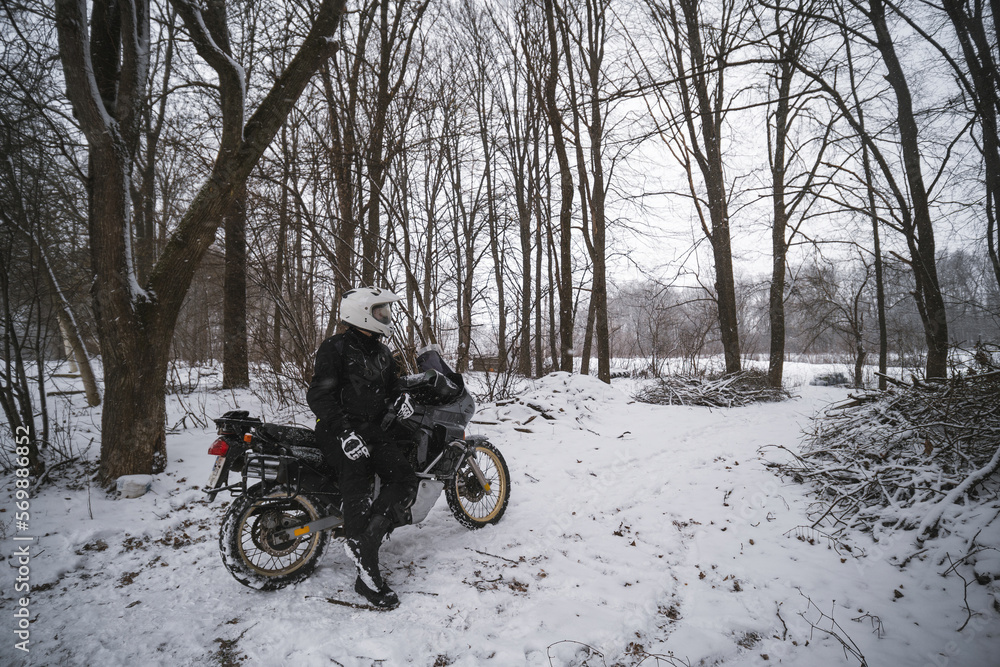 Motorcyclists enjoy extreme winter riding on a motorcycle, snowy forest, snowfall. The concept of transport and clothing for the cold season. Stupid ideas of grown men.