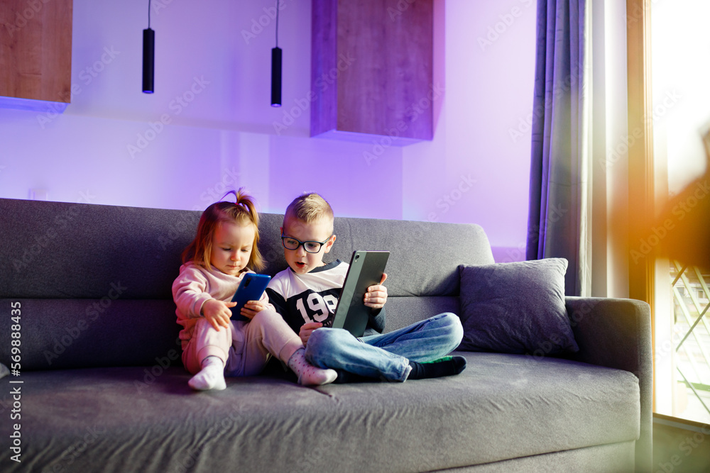 Danya and his sister Emilia play with mobile phones and tablets.