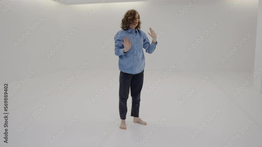 Slow motion young caucasian woman in casual clothes performing contemporary dance in white choreography studio, red hair curly female dancer training practice modern style performance in class Slow motion young caucasian woman in casual clothes performing contemporary dance in white choreography studio, red hair curly female dancer training practice modern style performance in class