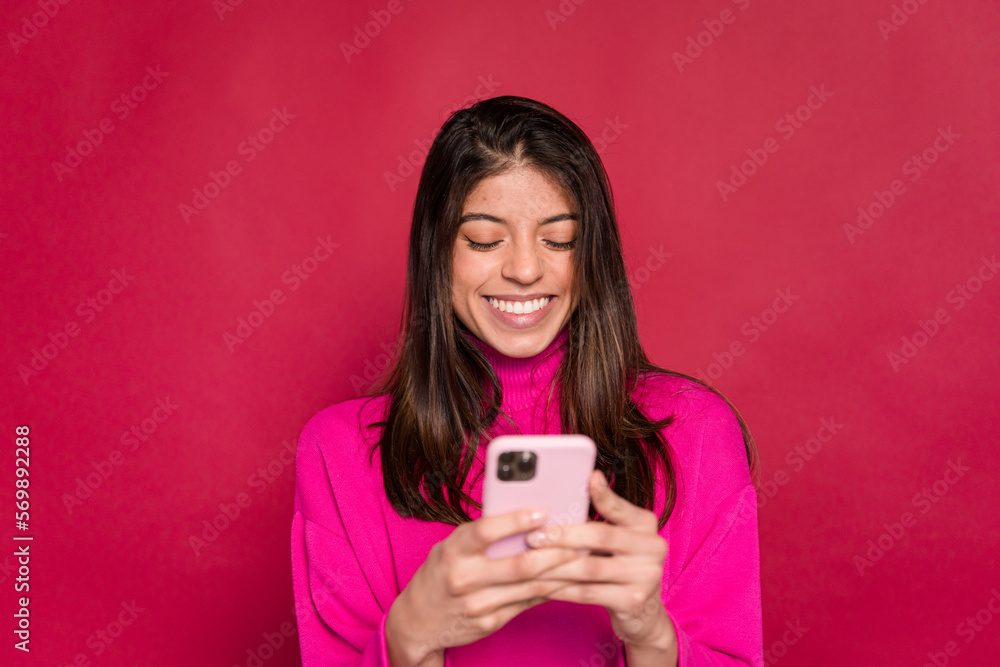 Smiling woman using smartphone against red background Smiling woman using smartphone against red background