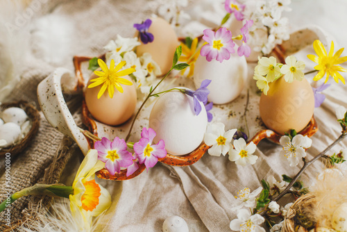 Canvas Print Stylish easter eggs and blooming spring flowers on linen fabric background