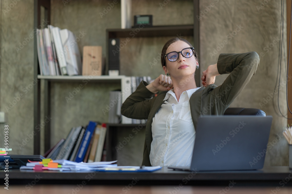 Young woman pleasantly smiling raising her hands upright while sitting at the workplace. Secretary doing warm-up after work. Young woman pleasantly smiling raising her hands upright while sitting at the workplace. Secretary doing warm-up after work.