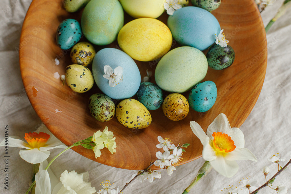Rustic easter still life. Stylish easter eggs and blooming spring flowers in wooden bowl on linen fabric. Happy Easter! Natural painted eggs and blossoms on rural table Rustic easter still life. Stylish easter eggs and blooming spring flowers in wooden bowl on linen fabric. Happy Easter! Natural painted eggs and blossoms on rural table
