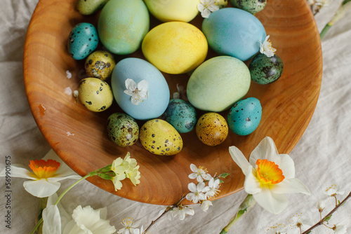 Fototapeta Naklejka Na Ścianę i Meble -  Rustic easter still life. Stylish easter eggs and blooming spring flowers in wooden bowl on linen fabric. Happy Easter! Natural painted eggs and blossoms on rural table