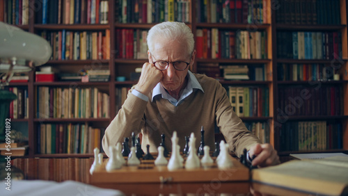 Photography Serious grandmaster thinking over chess composition, sitting at the library, hob