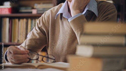 Fotografie Male academic studying scientific literature in the library, pile of books on ta