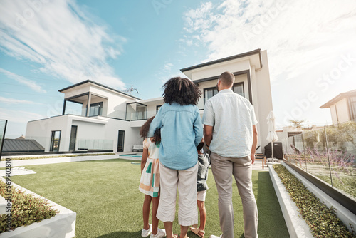 Love, new house and family in their backyard together looking at their property or luxury real estate. Embrace, mortgage and parents with their children on grass at their home or mansion in Canada.