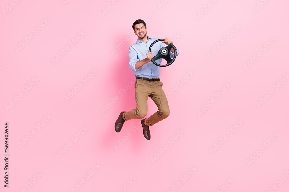 Full body length photo of young jumping carefree active businessman trying drive steering wheel his new sport car isolated on pink color background