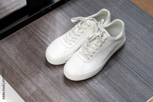 Pair of new stylish white unisex sneakers on wooden table