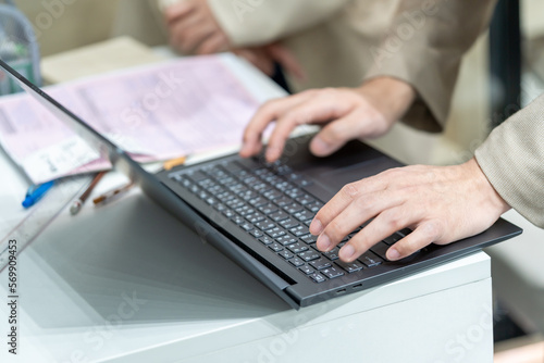 Employee’s hand using office computer Typing an email on a computer keyboard and doing online research working in an office.