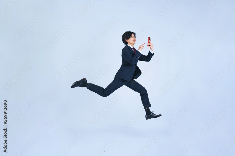 スマホを使いながらジャンプする男性 スマホを使いながらジャンプする男性