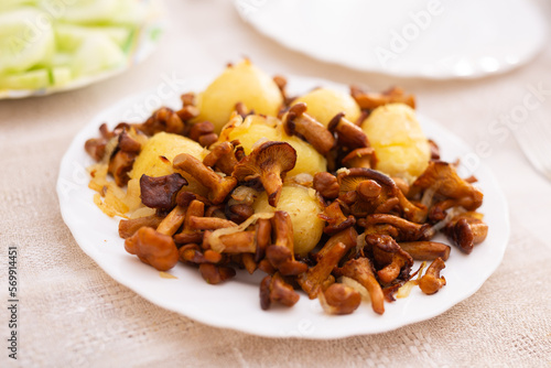 appetizing fried chanterelle mushrooms with new potatoes on white plate