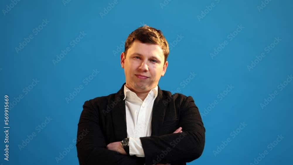 Handsome businessman in suit crossing his arms to his chest, shaking his head and listening on blue background Handsome businessman in suit crossing his arms to his chest, shaking his head and listening on blue background