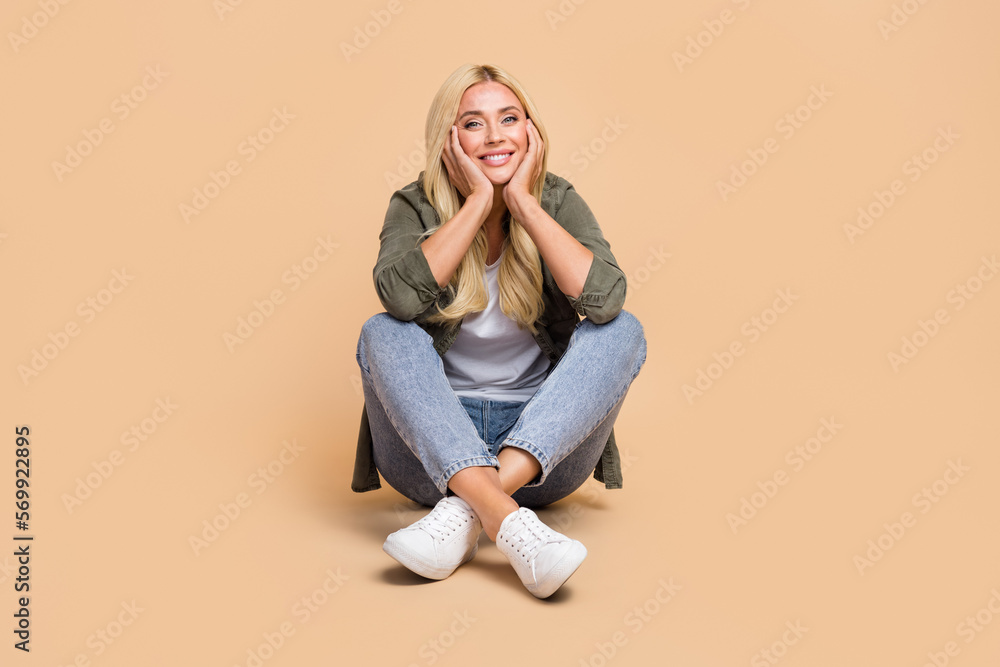 Photo of pretty lovely cheerful lady wear comfort khaki clothes enjoy free time sitting near empty space isolated on beige color background Photo of pretty lovely cheerful lady wear comfort khaki clothes enjoy free time sitting near empty space isolated on beige color background