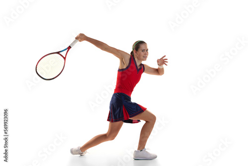 Studio shot of active teen girl, professional tennis player training with tennis racket over white background. Sport, fashion, ad, action, motion, achievement concept