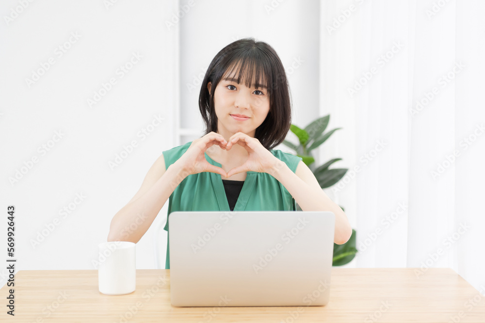手でハートの形を作って見せる若い女性