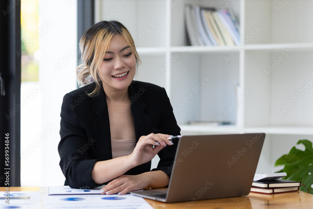 Portrait of attractive young business woman working with laptop and documents on office desk.