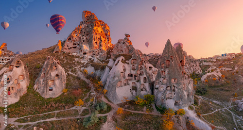 Ancient town of Uchisar castle with hot air balloons at sunset Goreme national park, Cappadocia Turkey, aerial top view