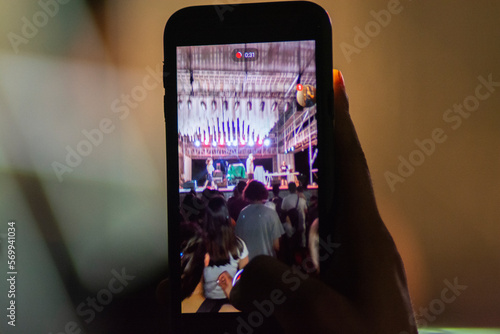 Manos sujetando teléfono móvil grabando un festival de música