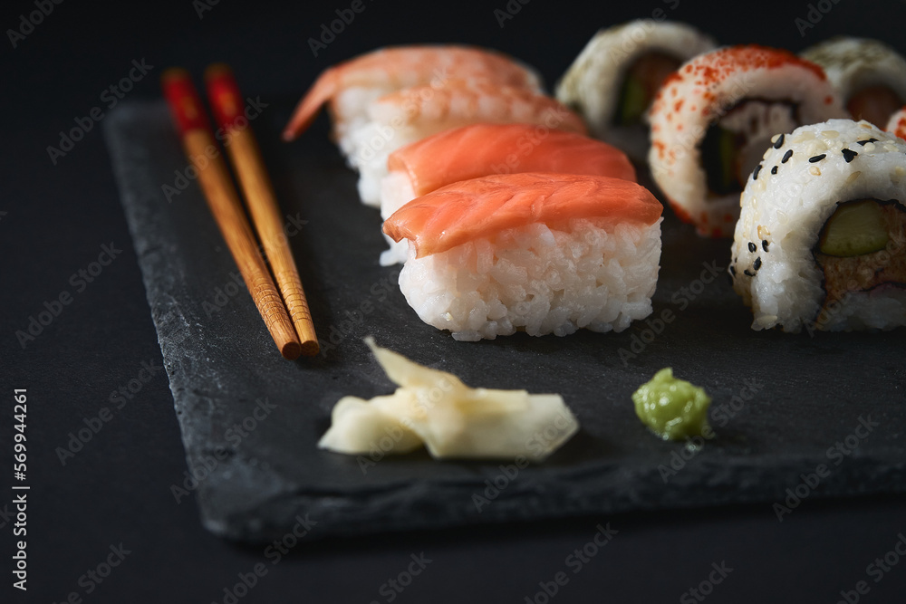 Delicious sushi rolls on board with chopsticks Delicious sushi rolls on board with chopsticks