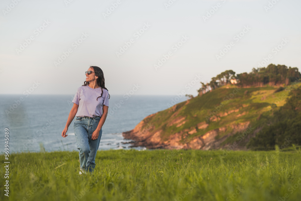 Happy woman walking on grassy hill near sea Happy woman walking on grassy hill near sea