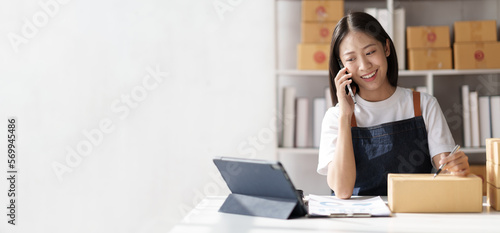Canvas Print Online business owner woman answer phone chat with customers and write down detail of customer who deliver negotiated address to verify correct detail