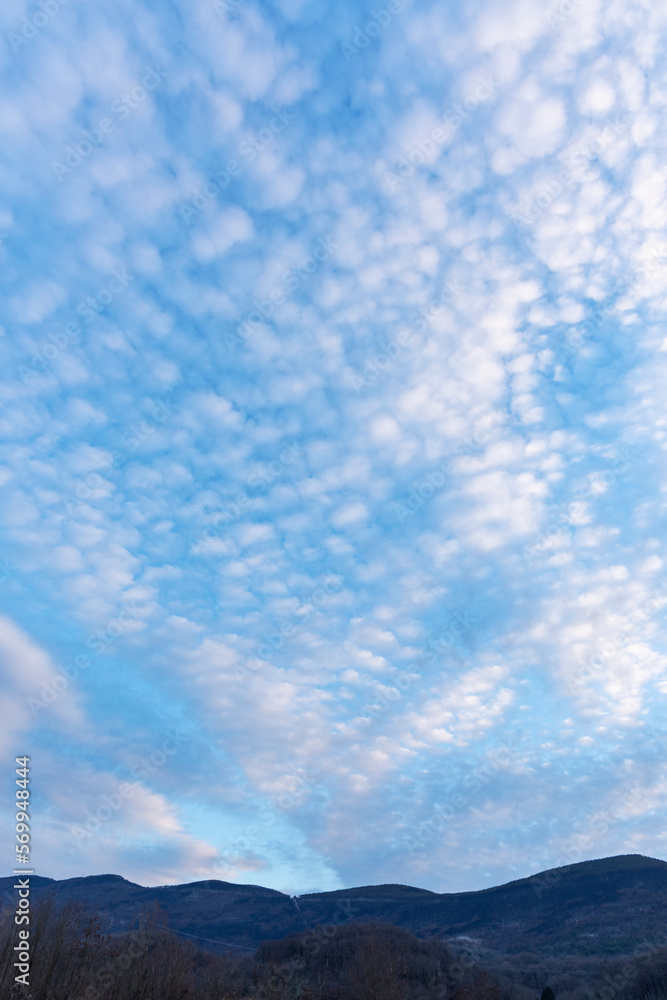 Obraz premium Distant hills under blue sky with cirrocumulus clouds, evening light