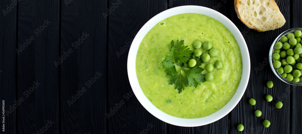 Pea soup in the white bowl on the black wooden background. Copy space. Top view. Pea soup in the white bowl on the black wooden background. Copy space. Top view.