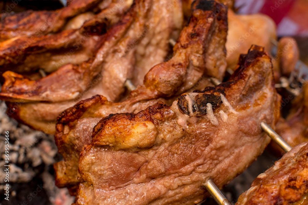 Several pieces of Liempo, or pork belly skewered on a spit and roasted on an oven at a roadside restaurant.