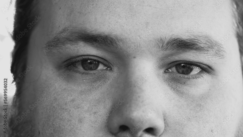 Naklejka premium One young man smiling at camera in monochromatic black and white image. Macro eyes