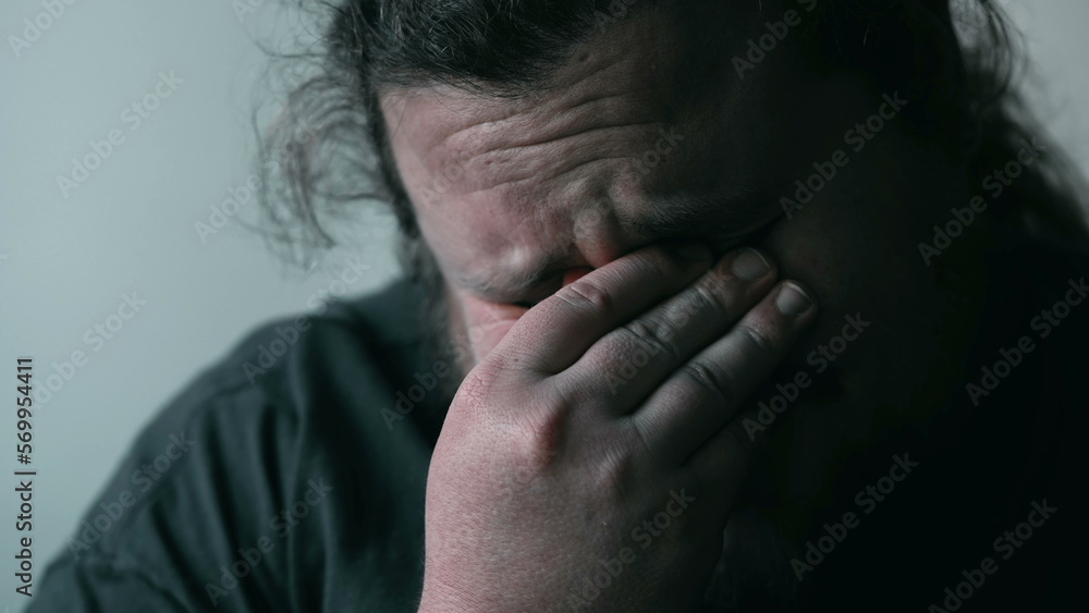 Desperate man crying in despair covering face in shame and regret. Person suffering from emotional pain. Depression concept Desperate man crying in despair covering face in shame and regret. Person suffering from emotional pain. Depression concept