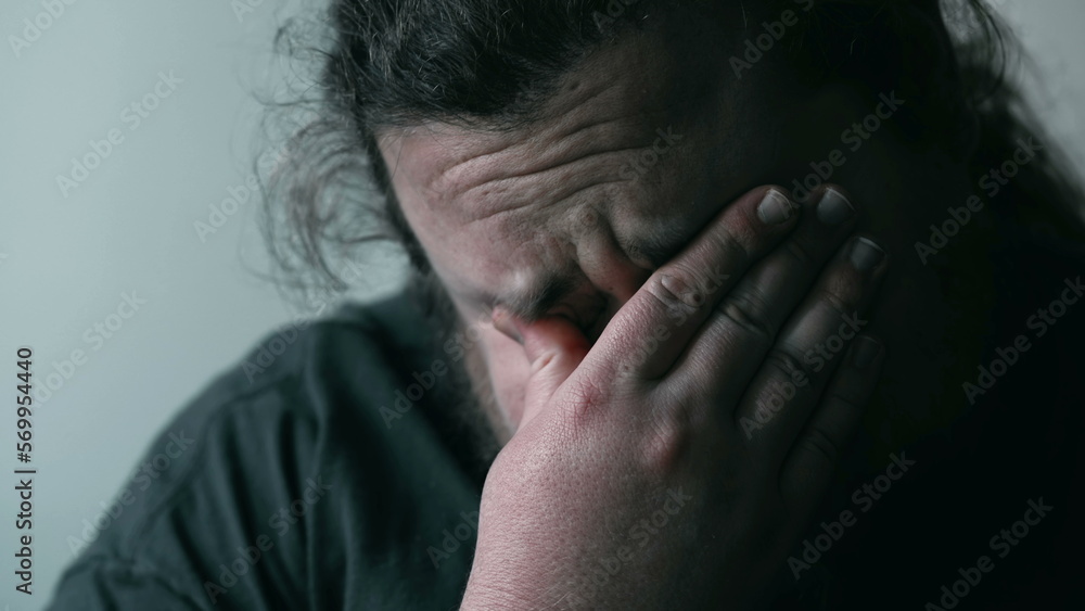 Desperate man crying in despair covering face in shame and regret. Person suffering from emotional pain. Depression concept Desperate man crying in despair covering face in shame and regret. Person suffering from emotional pain. Depression concept