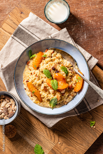 Millet groats dessert with caramelised apricots, almonds and mint leaves. Breakfast bowl.