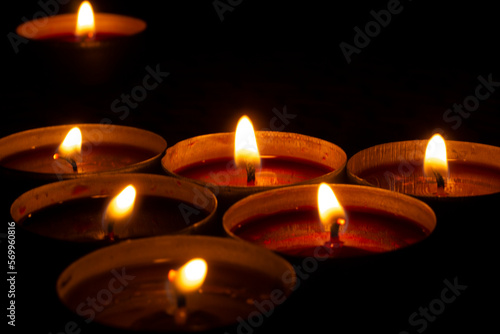 Candles burn in dark. Candle flames. Lights on black background.