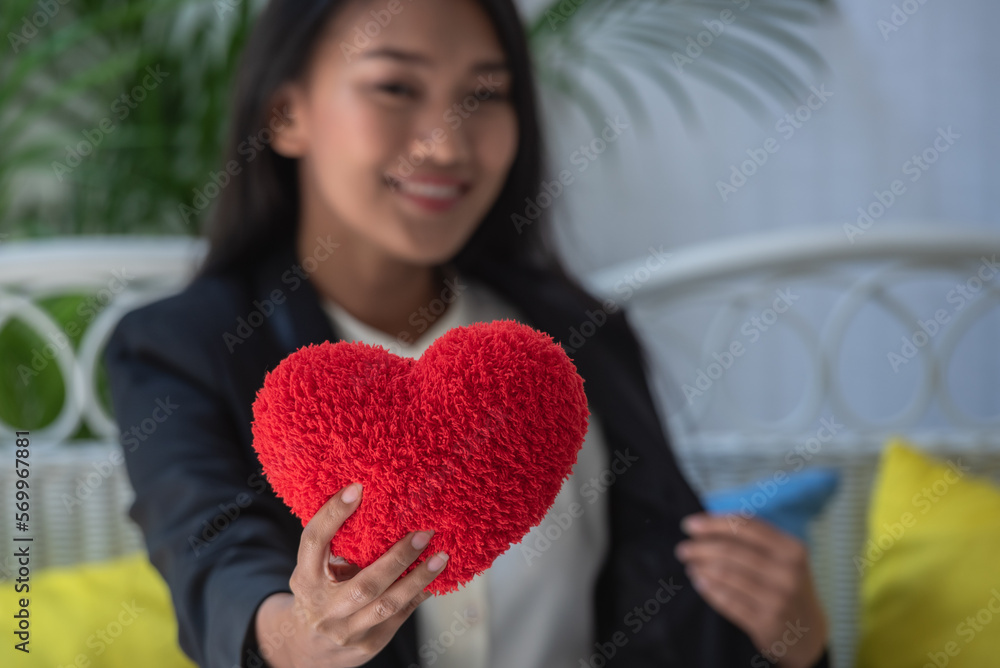 Asian woman show red heart pillow in hands for romantic date at valentine. Girl holding red pillow symbol for show love. happy in love relaxing looking in eye smiling valentine day Asian woman show red heart pillow in hands for romantic date at valentine. Girl holding red pillow symbol for show love. happy in love relaxing looking in eye smiling valentine day