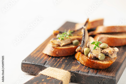 Sandwich - smorrebrod with sprats and capers on wooden board. Danish cuisine. Copy space