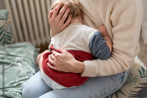 Konstfotografi Woman with baby, mother gently hugs her child with both hands, the child sits on her lap, the baby presses his head to the parent's body