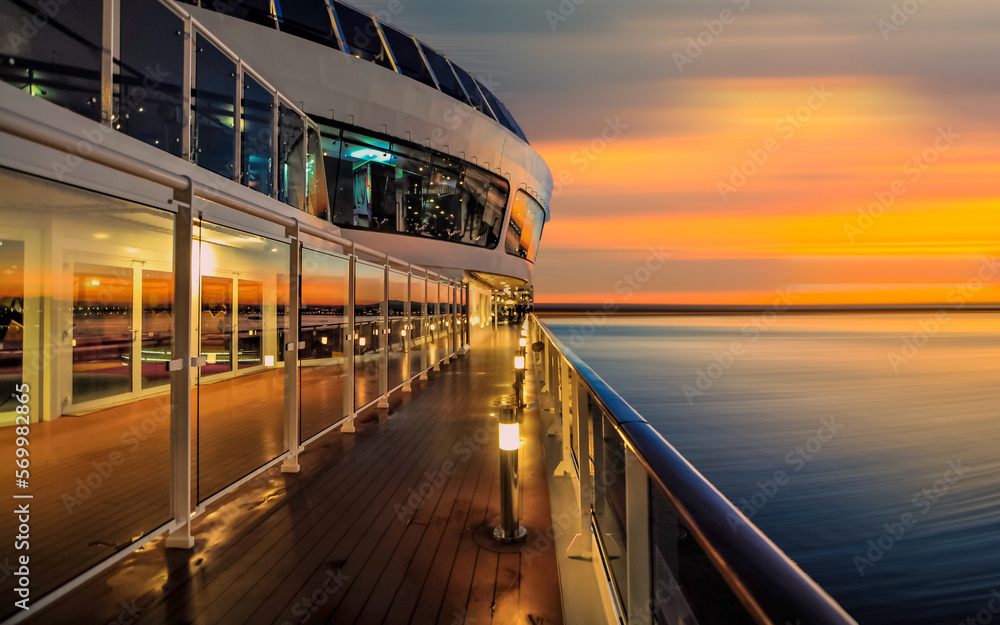 Pont promenade d'un navire de croisière en navigation avec coucher de soleil.	