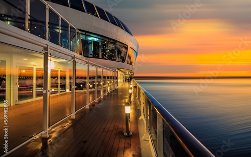Pont promenade d'un navire de croisière en navigation avec coucher de soleil. 