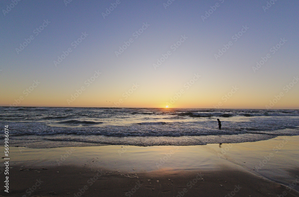 niños corriendo hacia el mar en la puesta del sol