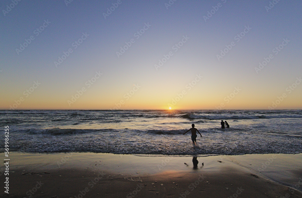 niños corriendo hacia el mar en la puesta del sol