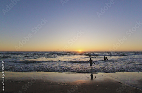 niños corriendo hacia el mar en la puesta del sol