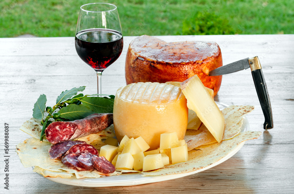 Vassoio con tipici salumi e formaggio sardi e calice di vino rosso