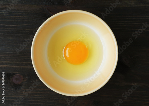 Top View of a Fresh Raw Egg Yolk and White in a Bowl Isolated on Wooden Table	
