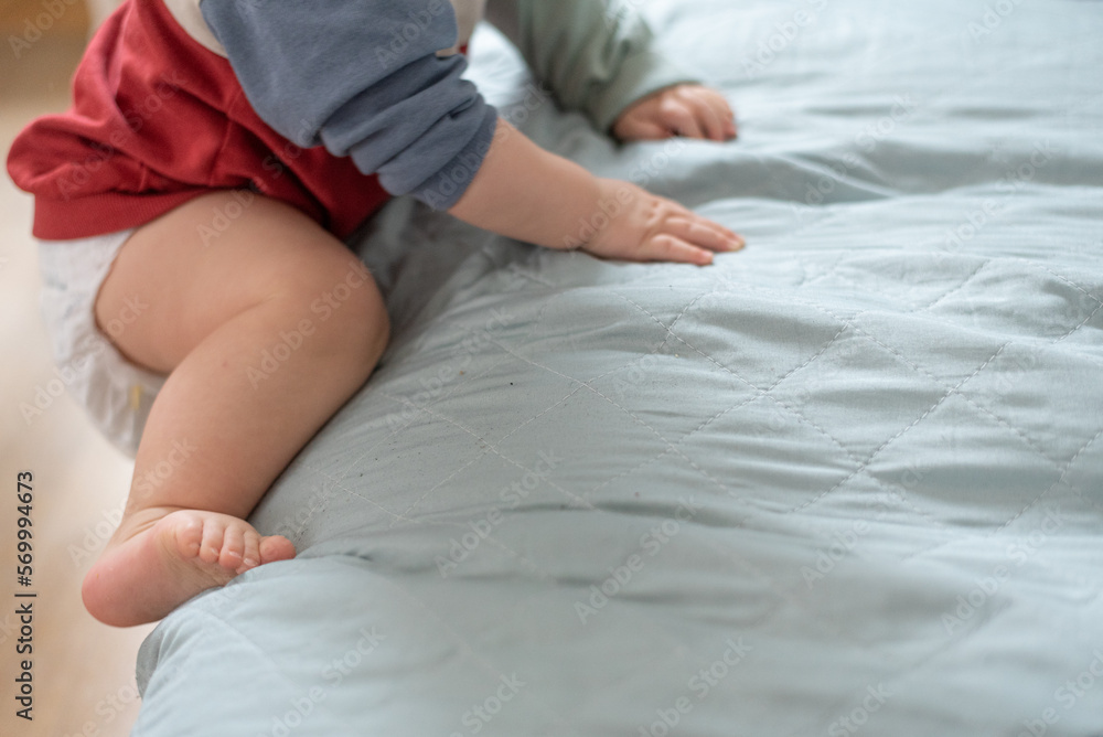 Child trying to climb on the couch. The arms and legs of a small child. Background with space for text. Child trying to climb on the couch. The arms and legs of a small child. Background with space for text.