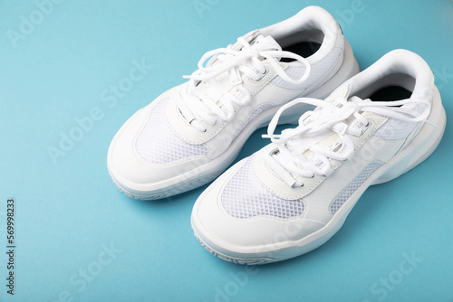 Pair of white shoes on a blue paper background. Sport shoes. Unisex. Street style.