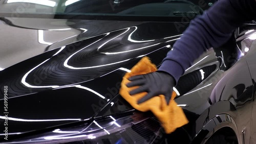 A man cleaning car with microfiber cloth, car detailing concept. Car service worker polishing car with microfiber cloth.