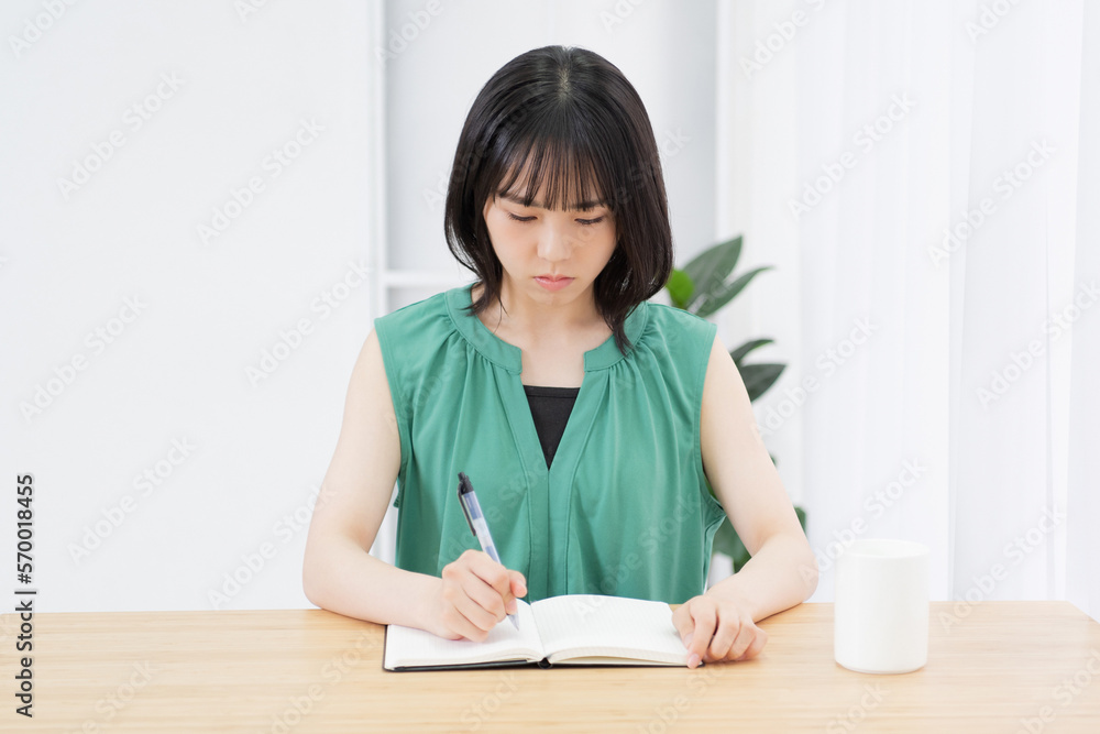 ノートに文字を書いている若い女性
